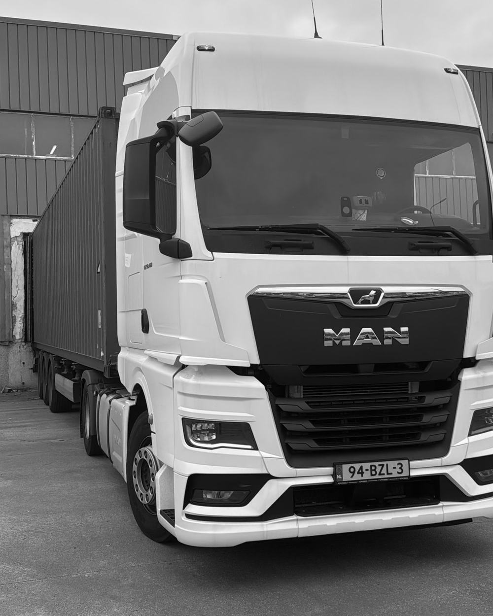 Trekker van ORNIFA met een zeecontainer bij een loods